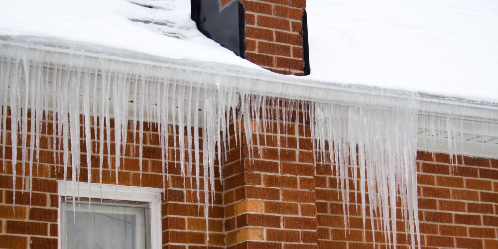 A red brick house with ice dams building up frozen water in Kitchener-Waterloo, Ontario.