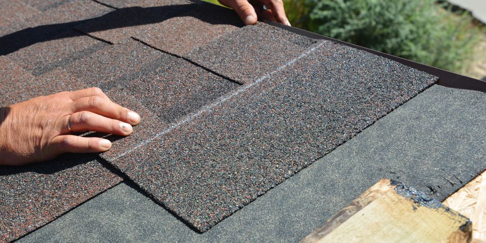 A close-up photo of a man installing a new shingle during a Roof replacement in Kitchener Waterloo.