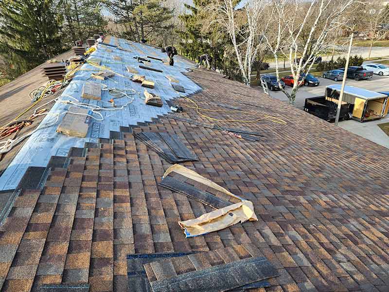 Quality Care Roofing installing new brown shingles on a large residential complex